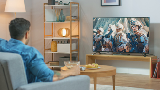 Homem sentado no sofá em frente a ecrã do televisor que está incluído o seguro multirriscos-habitação.